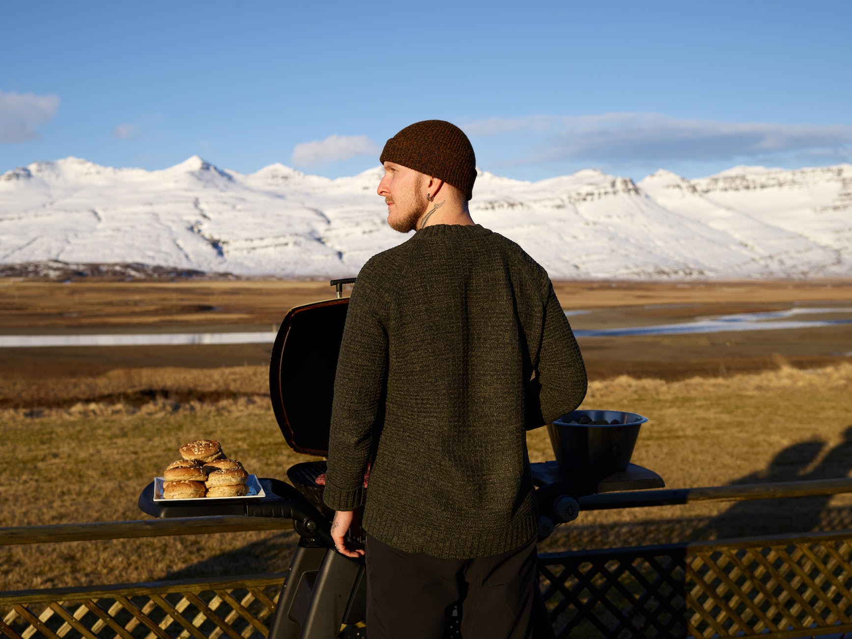 young man cooking hamburgers on grill in camp site