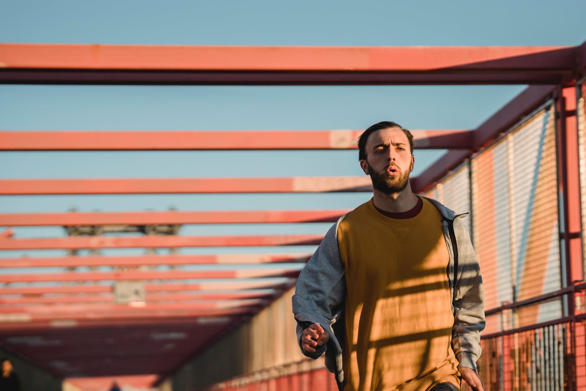 male jogger running on bridge in sunlight